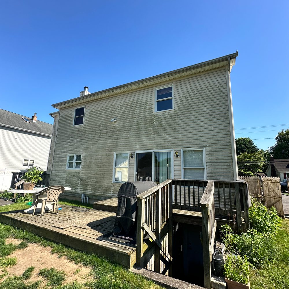 Rear of a house with dingy siding and deck before cleaning